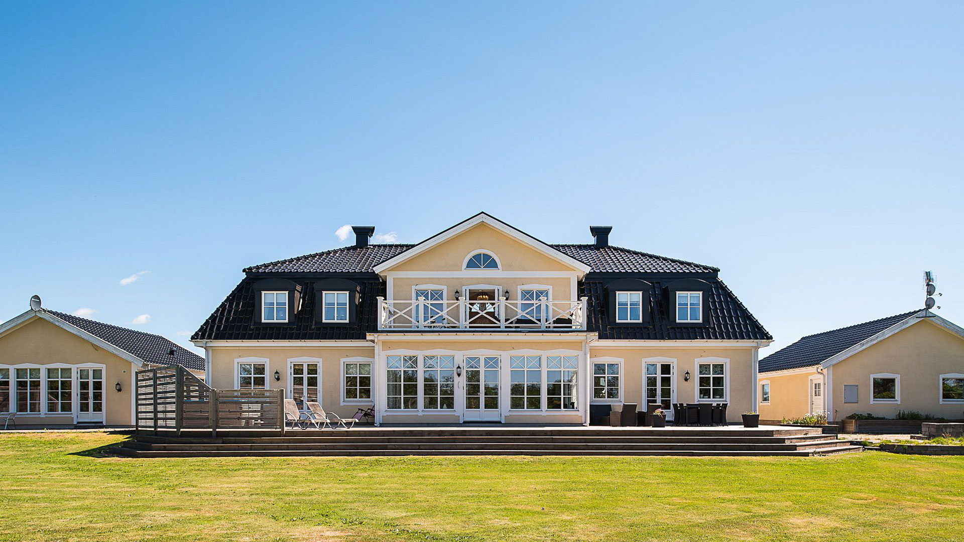 Stort ljusgult hus med vita knutar och svart tak